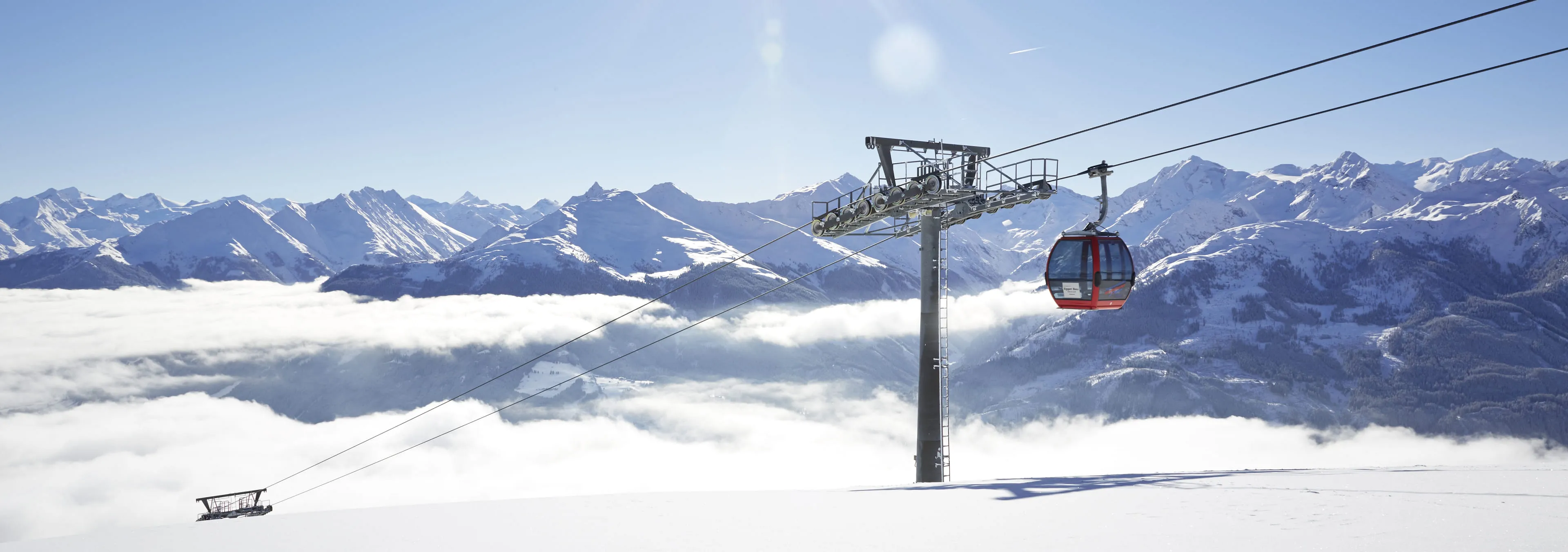 Seilbahn über schneebedeckte Berge in Mittersill, Wolken im Tal.