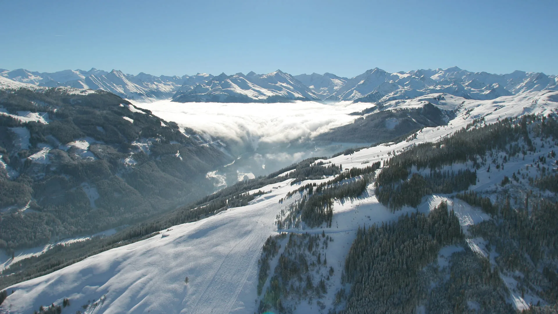 Luftaufnahme der Hohe Brücke mit schneebedeckten Bergen und Wolkenmeer