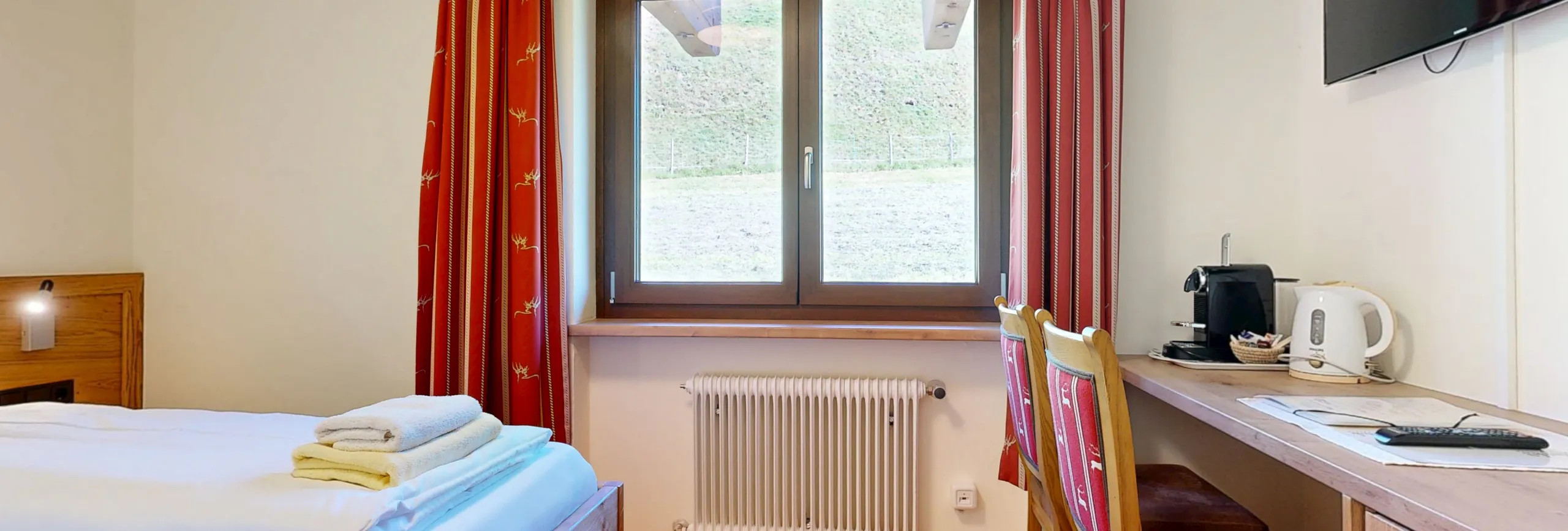 Helles Zimmer mit Fenster, Schreibtisch, Stuhl und Bett